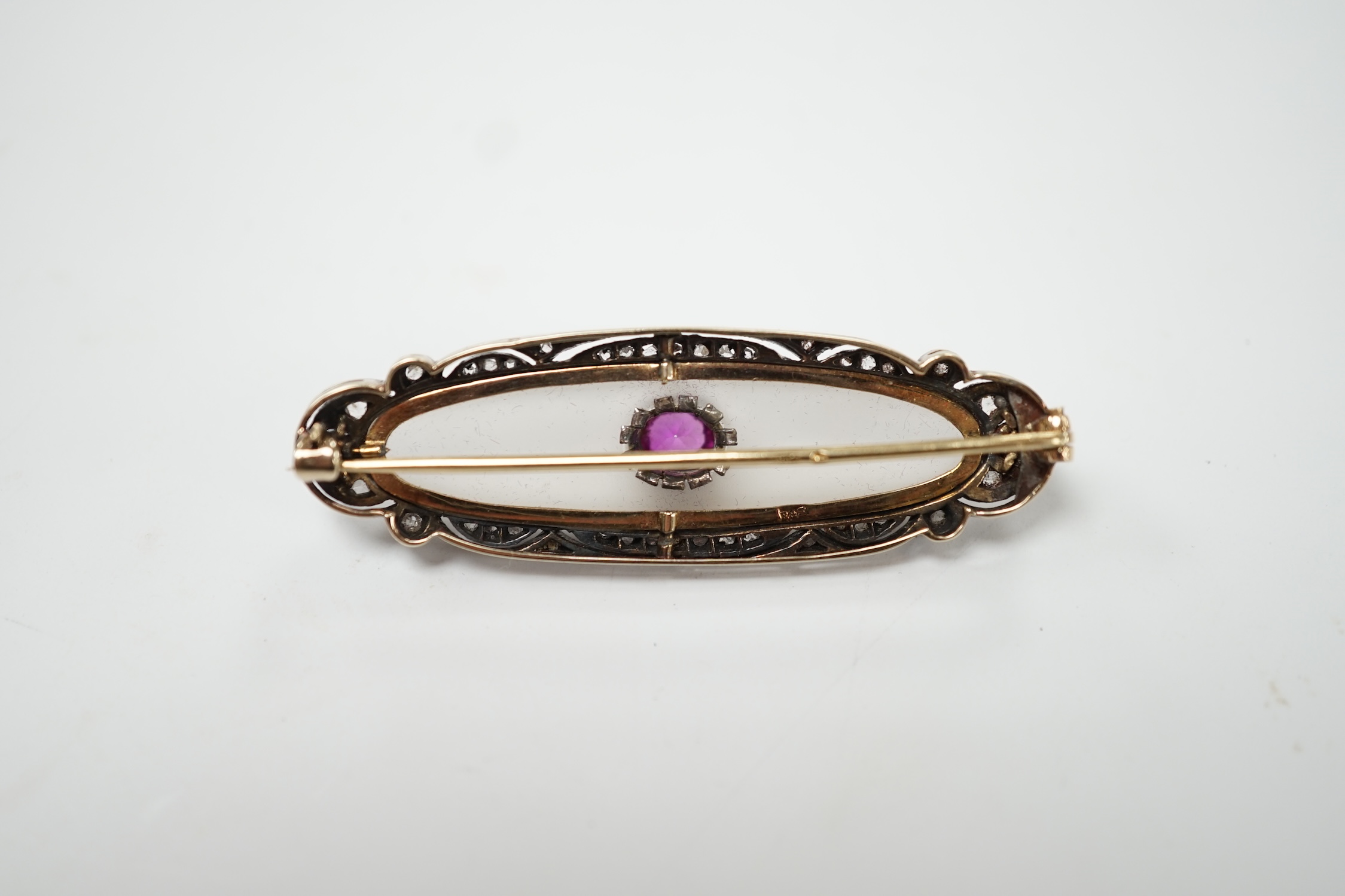 A 1920's yellow metal, diamond and single stone pink sapphire set rock crystal oval brooch, 48mm, gross weight 7.7 grams. Good condition.